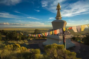 Colorado Meditation Retreat - Crestone, Colorado - Vova Kuperman - Camino Wellness Center. Buddhist stupa with prayer flags on a hilltop overlooking open landscape under blue sky.